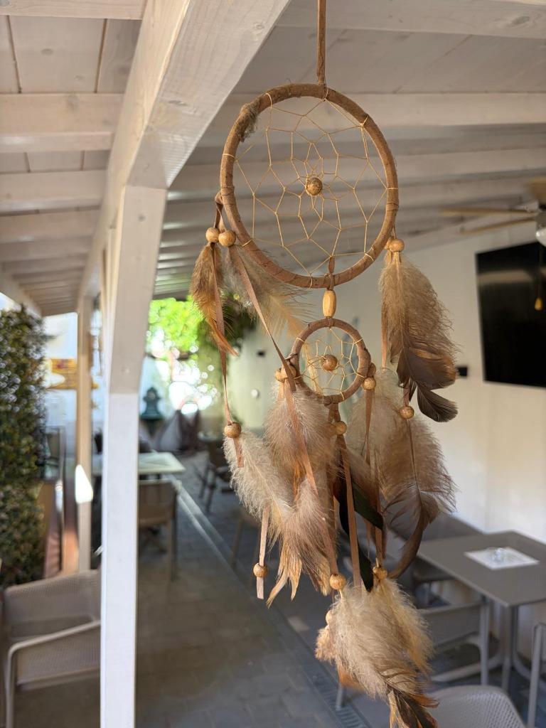 Bistro Papas terrace — dreamcatcher hanging from white wooden pergola beams